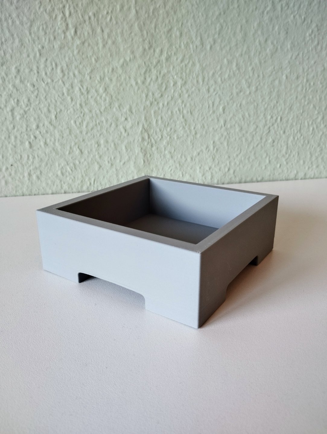 Minimalist bonsai pot holding a small plant, styled on a light wooden shelf
