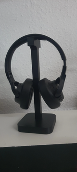 Headphone stand displayed on desk next to monitor and desk lamp