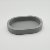 Minimalist rounded key tray on a wooden shelf holding keys and coins