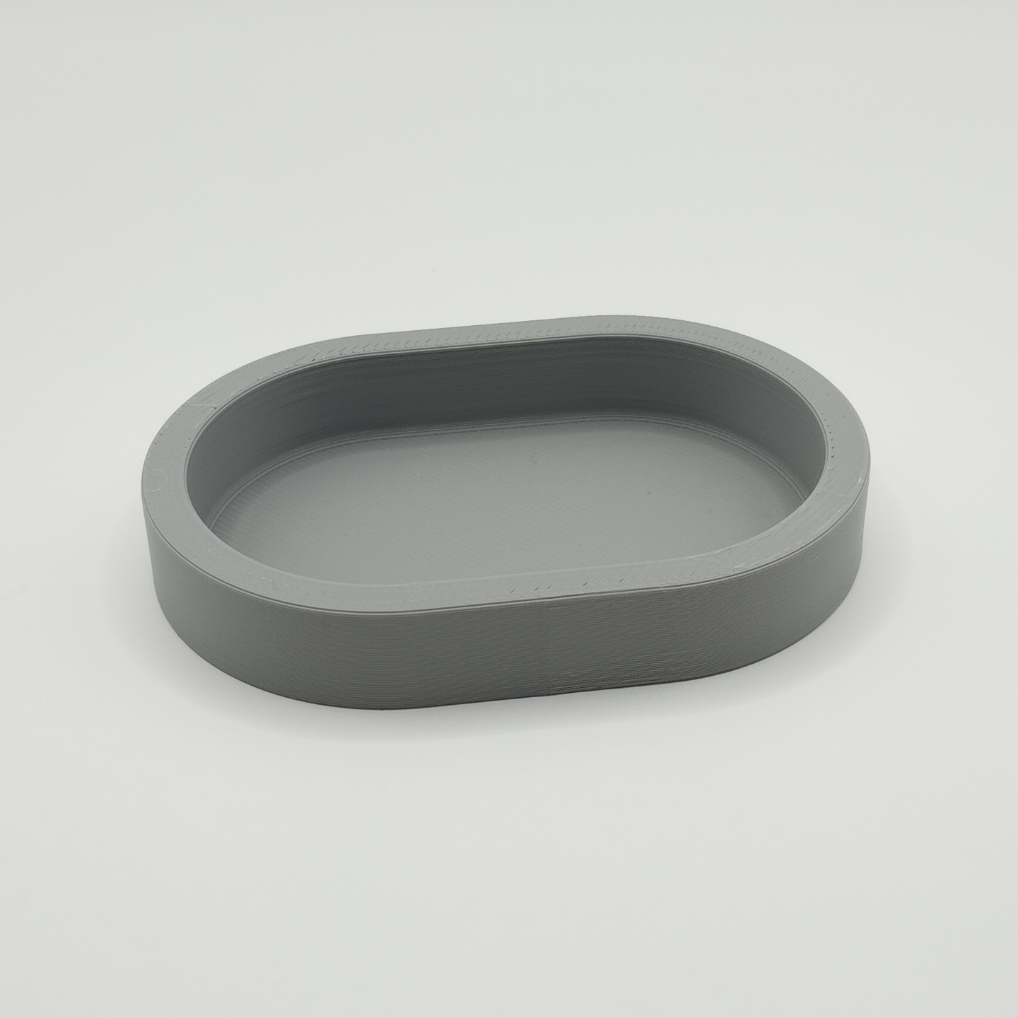 Minimalist rounded key tray on a wooden shelf holding keys and coins