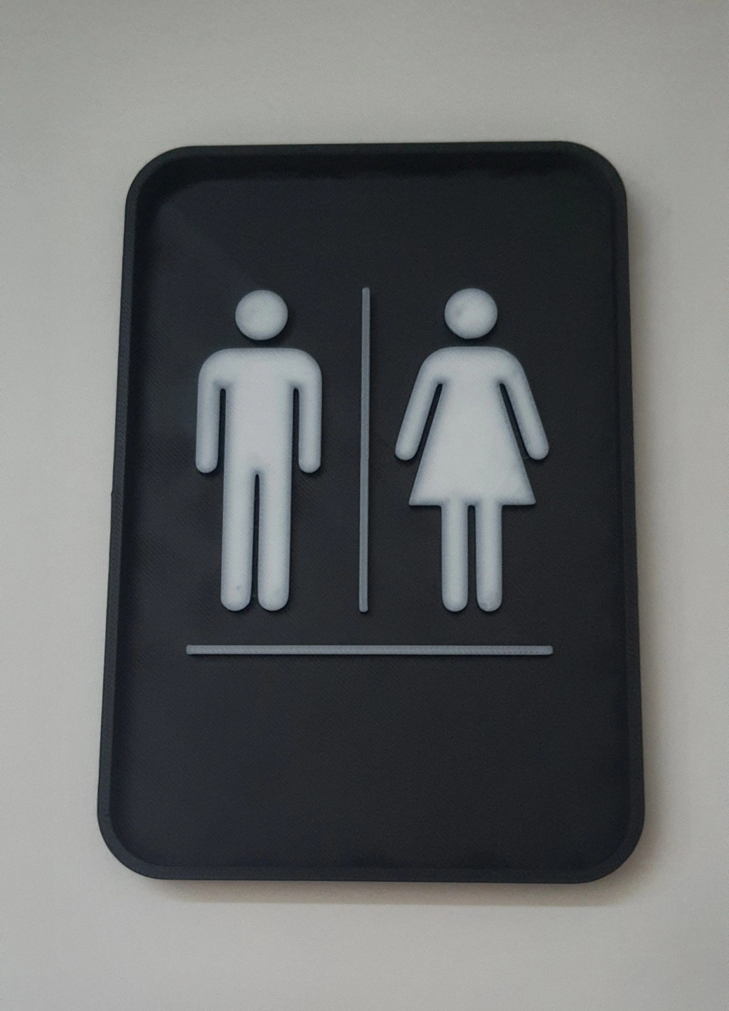 Detail of the toilet sign's crisp typography and neutral finish
