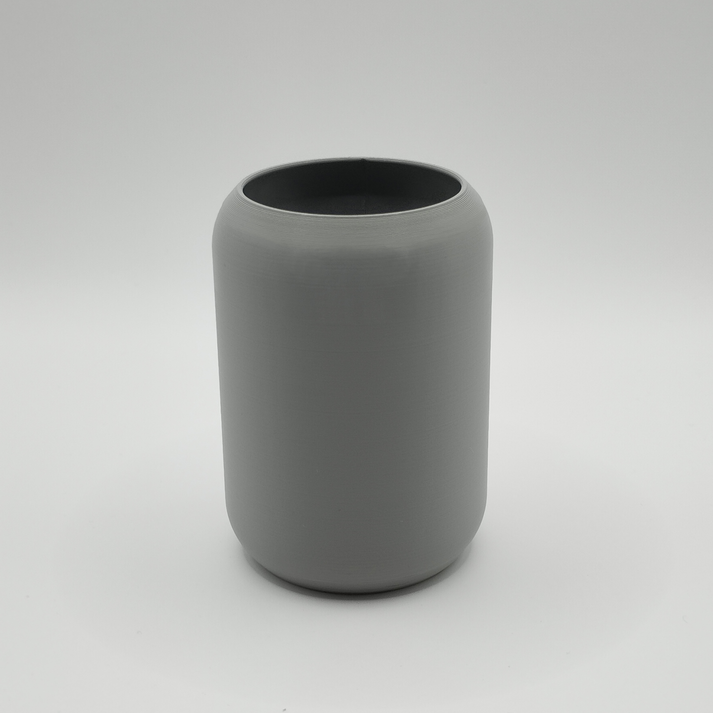 Minimalist rounded toothbrush holder on a bathroom shelf next to a mirror