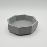 Minimalist geometric bowl displayed on wooden shelf in modern interior