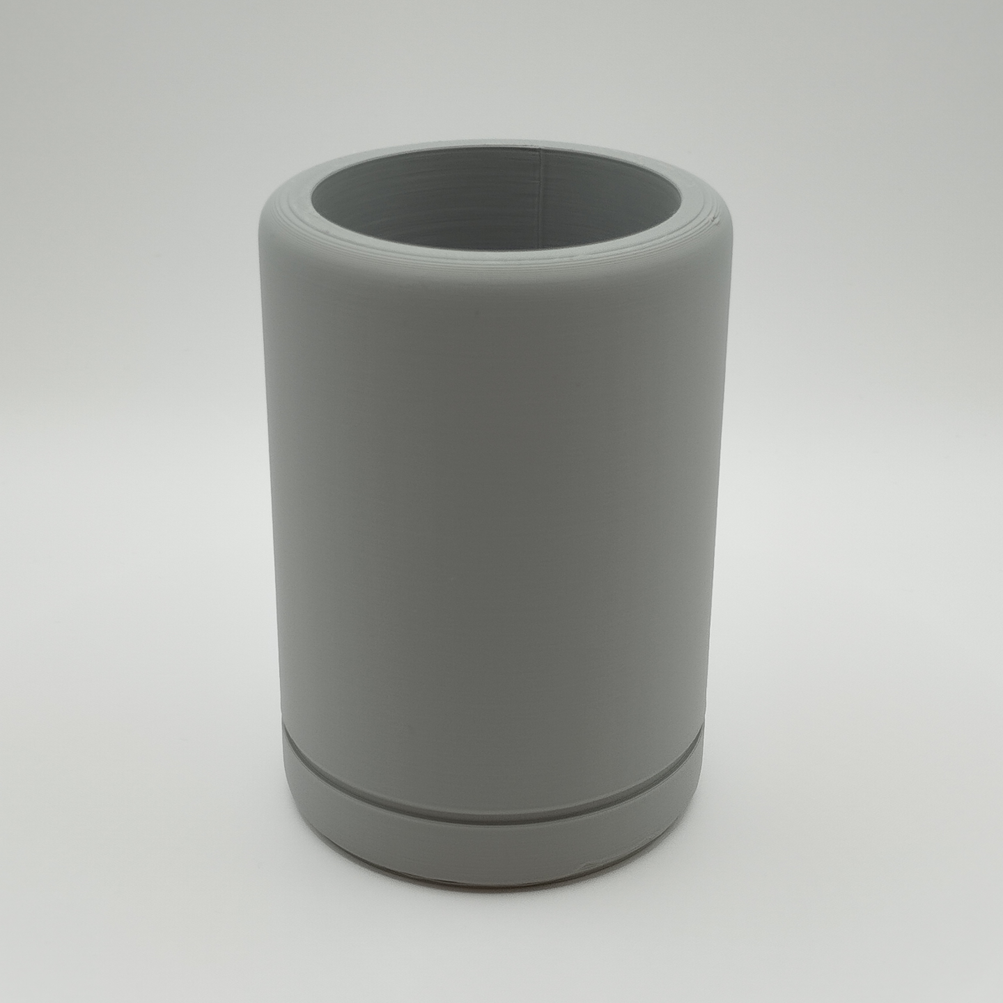 Minimalist round pencil holder on wooden desk with sketching supplies and open notebook