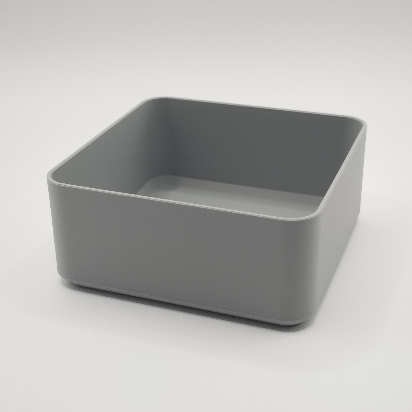 White minimalist square bowl caddy on wooden coffee table with remote and keys