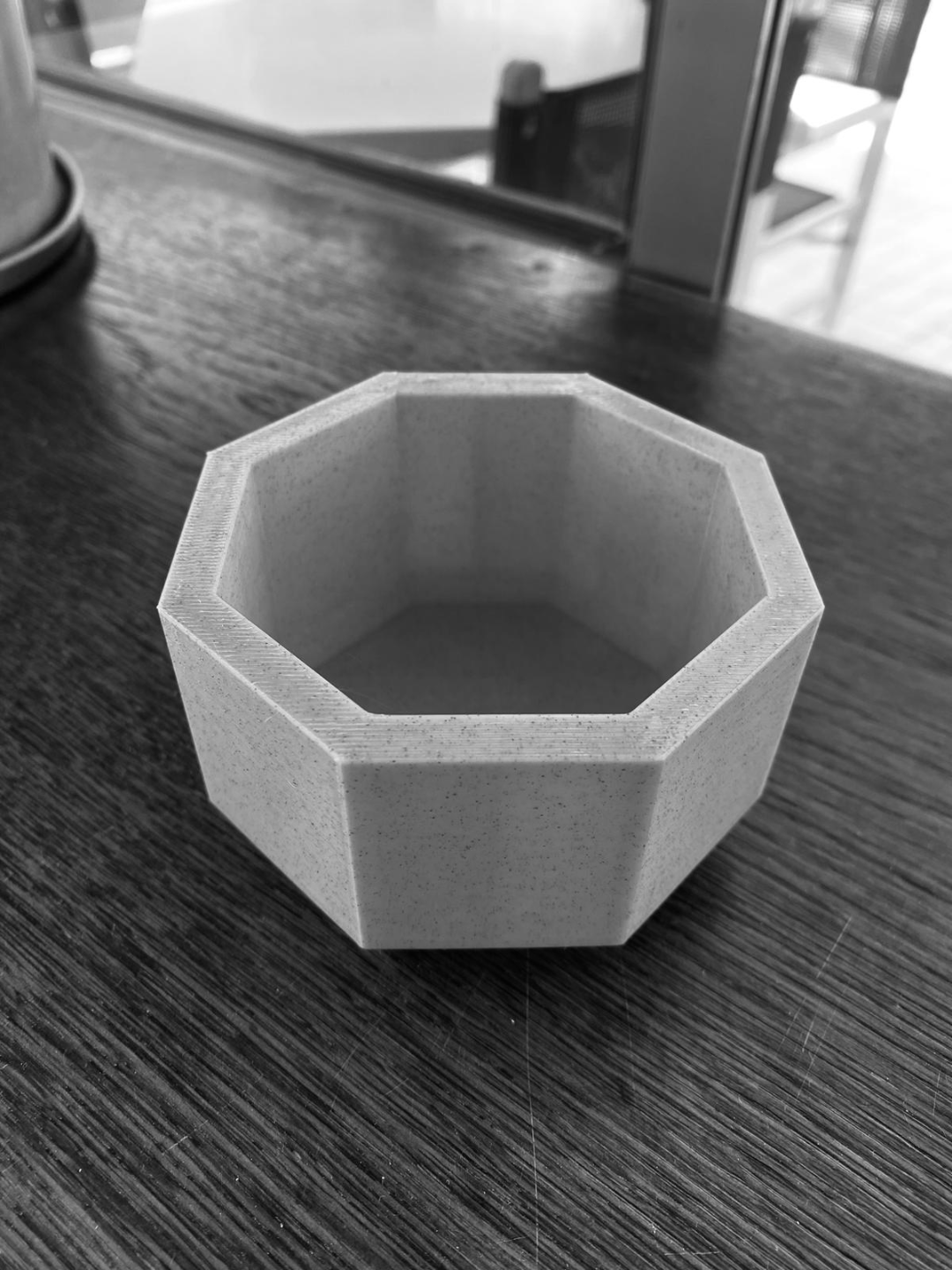 Octagonal planter styled on a white shelf with a small potted succulent inside