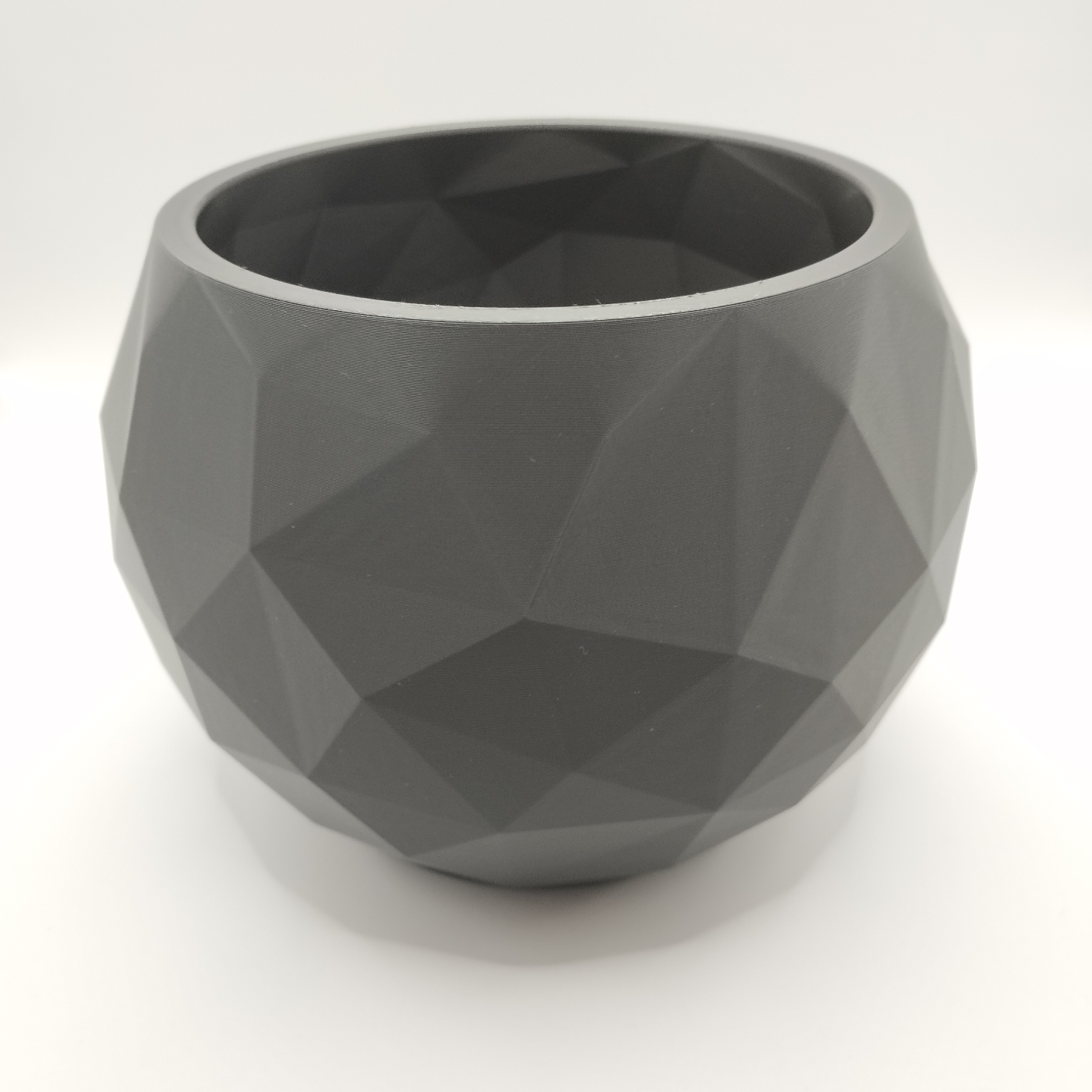Low poly bowl styled on white shelf with minimal home decor in soft Nordic interior