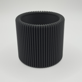 Ribbed pencil holder on desk holding pens and pencils in natural light