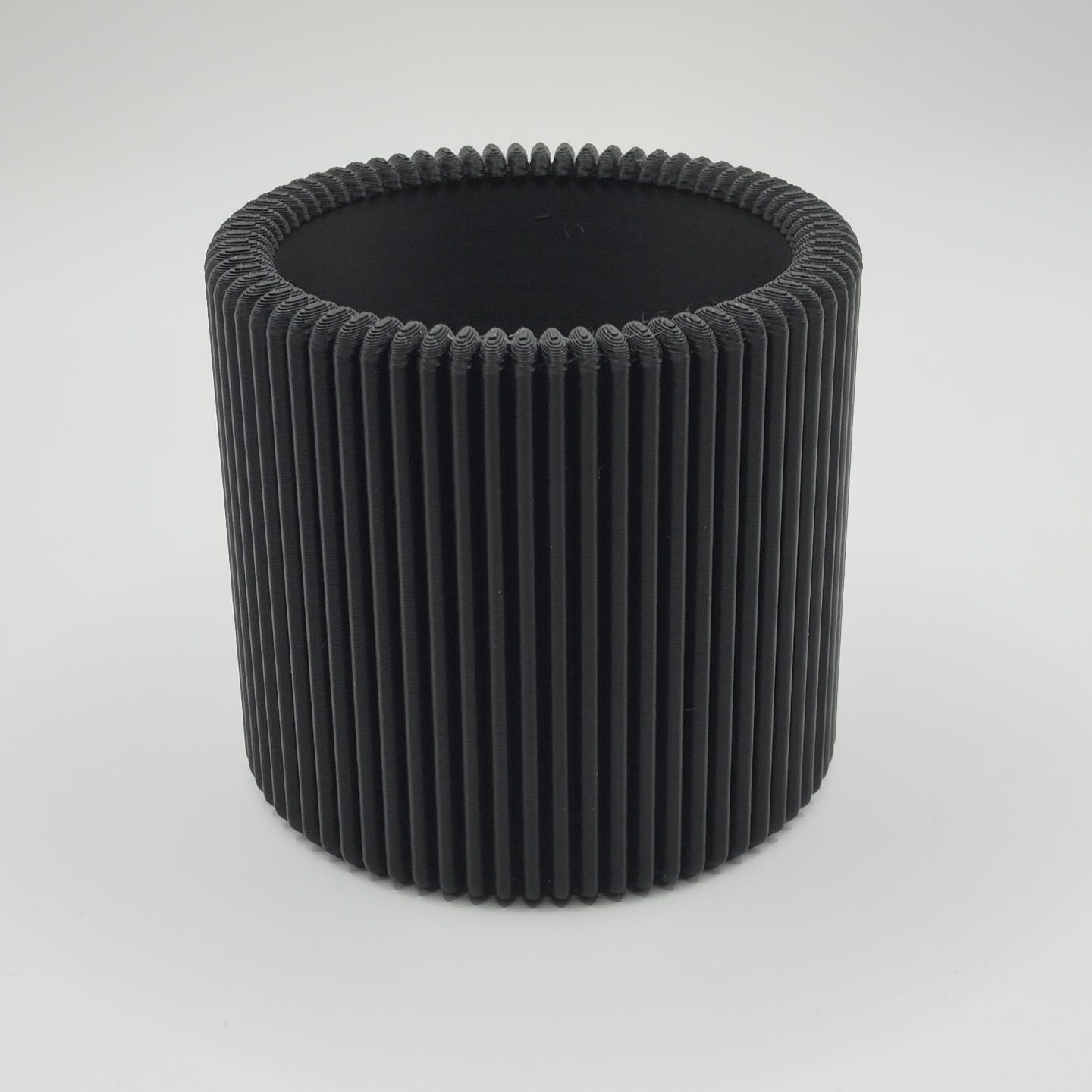 Ribbed pencil holder on desk holding pens and pencils in natural light