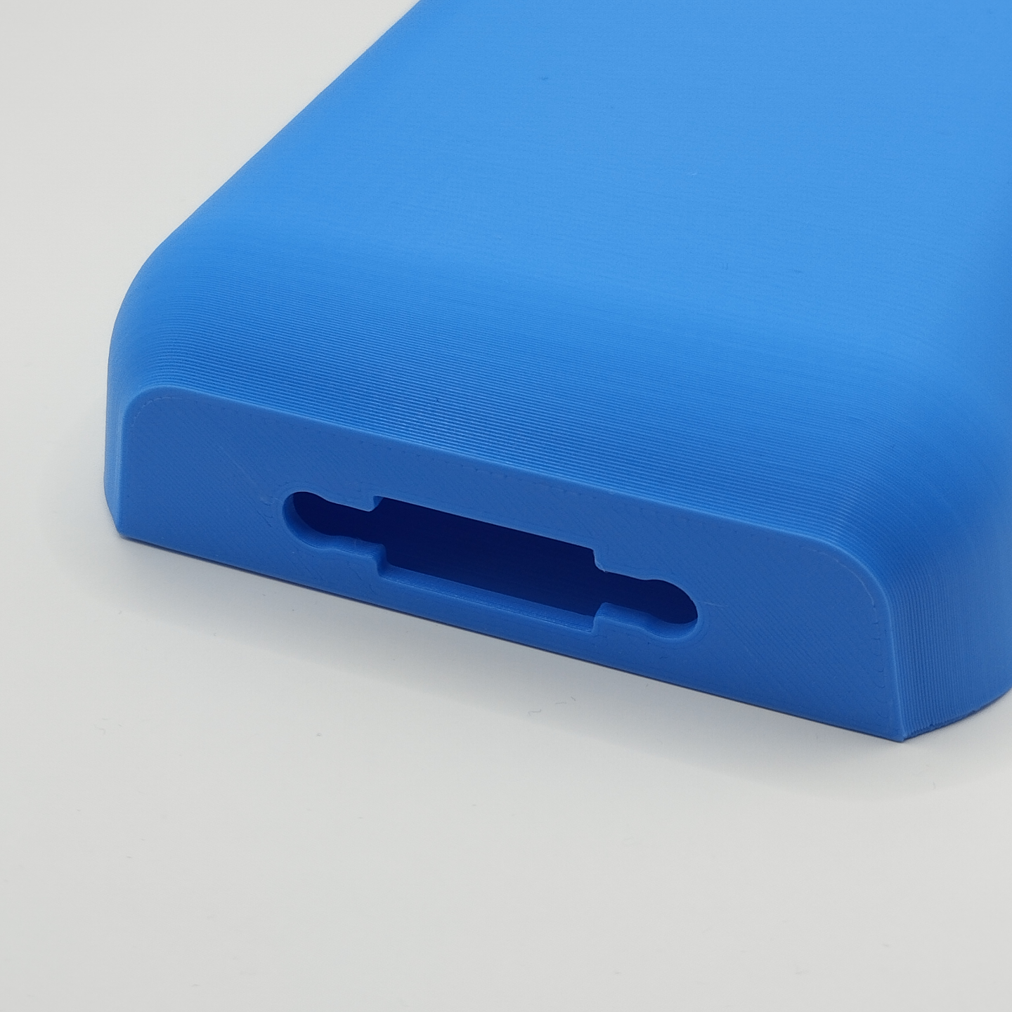 White wall-mounted phone holder with cable entry shown close-up