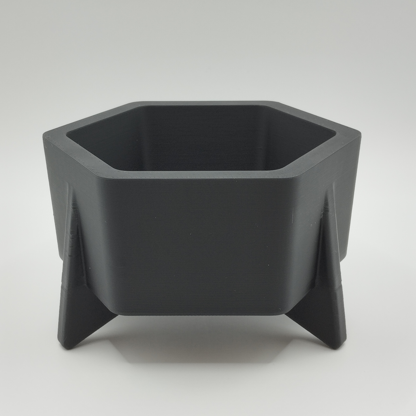Hexagonal mid-century planter on white shelf with small succulent