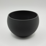 Key and coin catchall bowl styled on a light wooden desk next to a plant