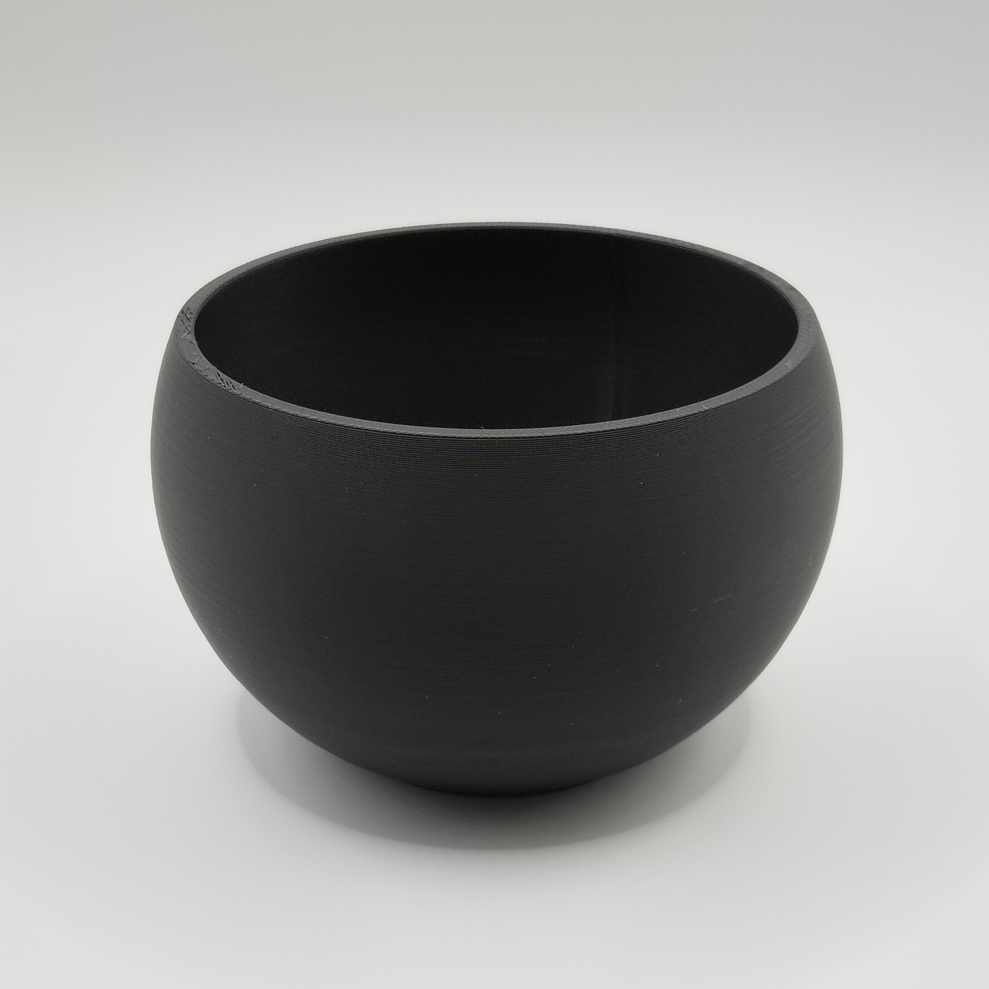Key and coin catchall bowl styled on a light wooden desk next to a plant