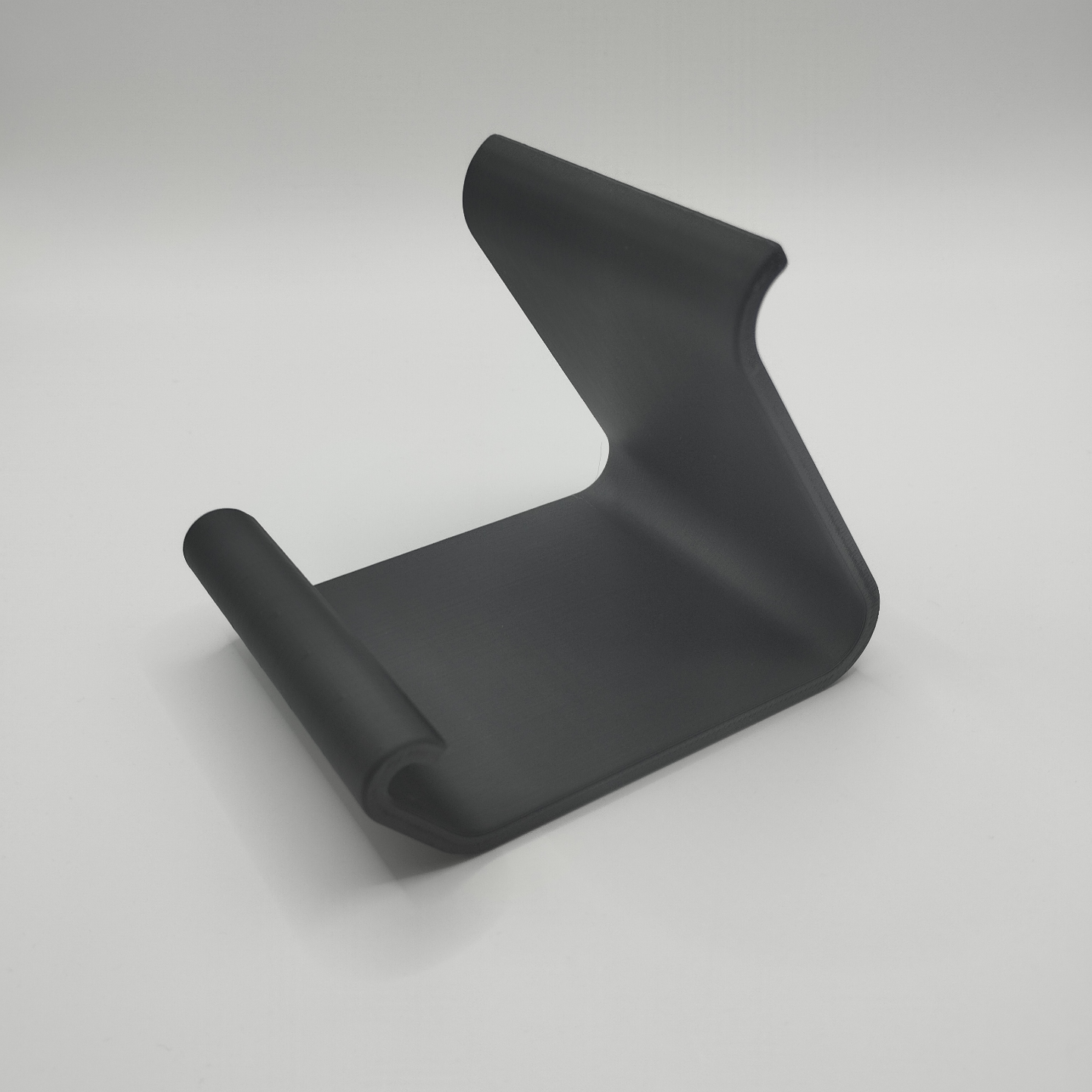 Curved smartphone holder on wooden desk displaying an iPhone