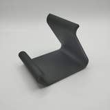 Curved smartphone holder on wooden desk displaying an iPhone