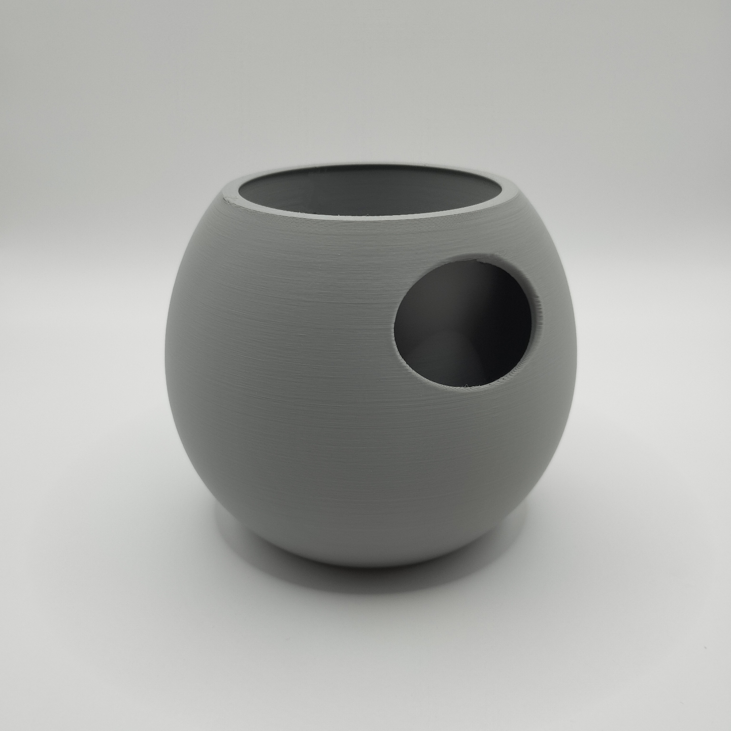 Self-watering plant pot on white shelf next to other decor objects in Scandinavian interior