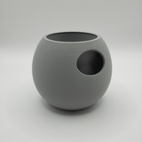 Self-watering plant pot on white shelf next to other decor objects in Scandinavian interior