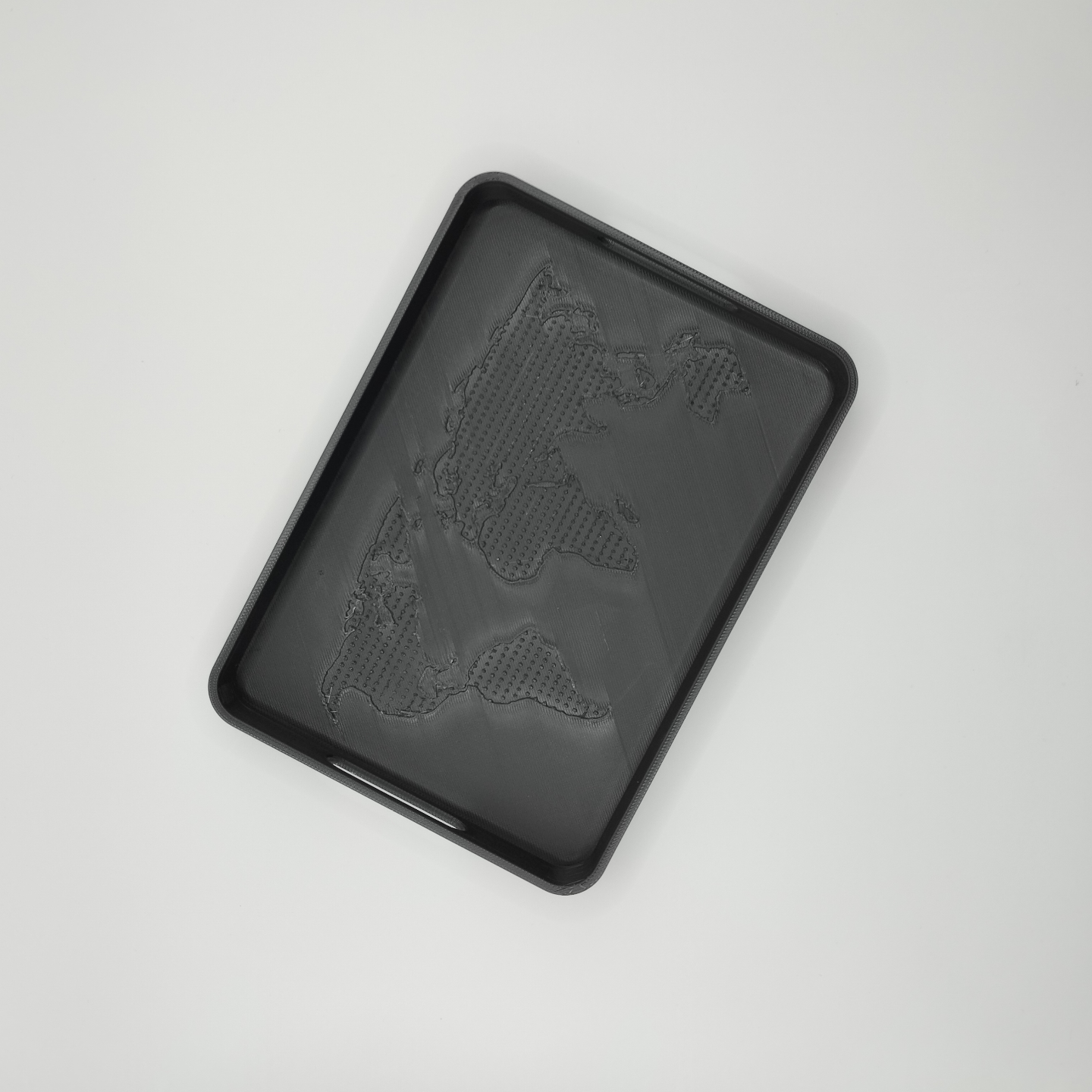 Close detail of OneWorld tray showing textured continent relief pattern