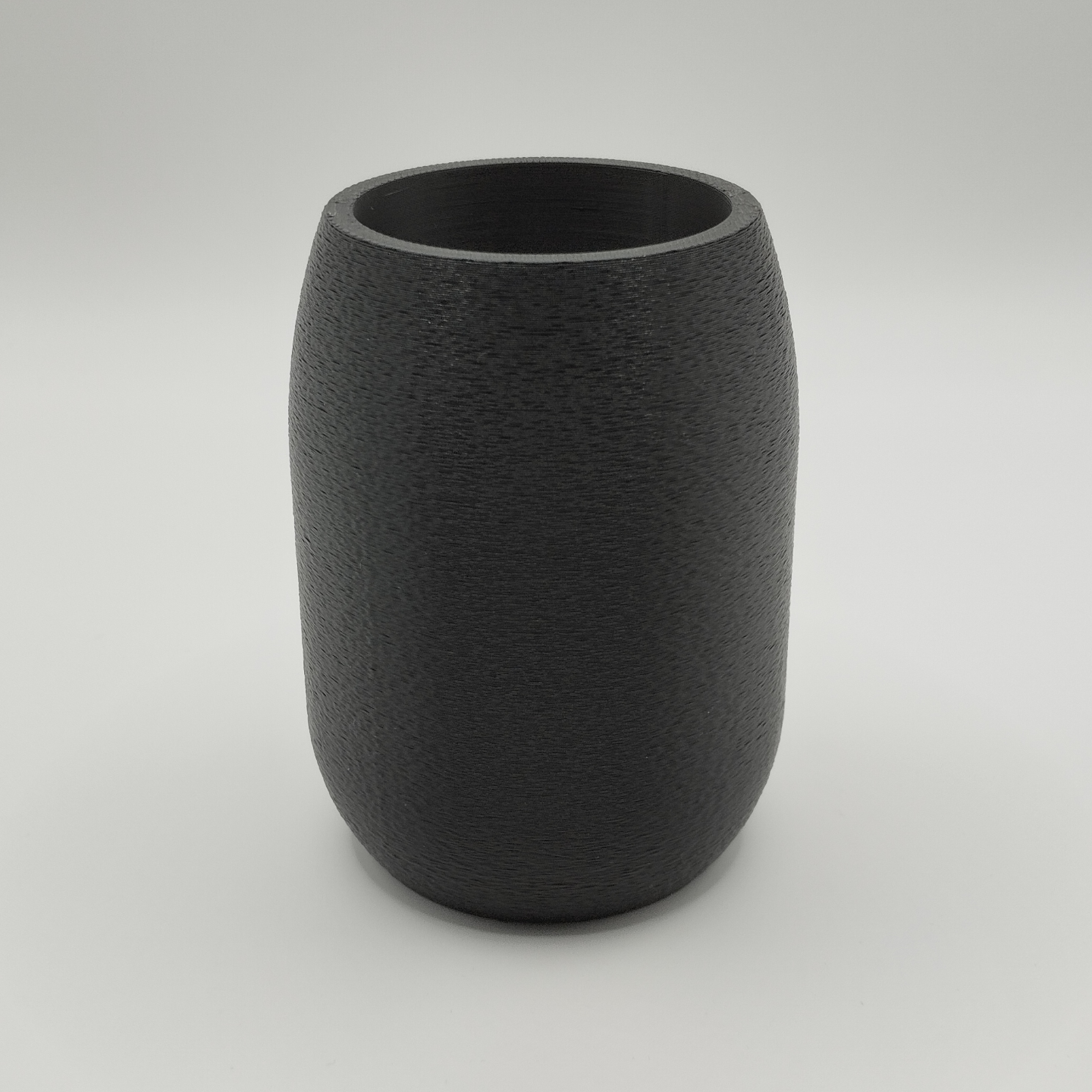 Round pencil holder filled with writing tools on minimalist desk