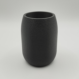Round pencil holder filled with writing tools on minimalist desk