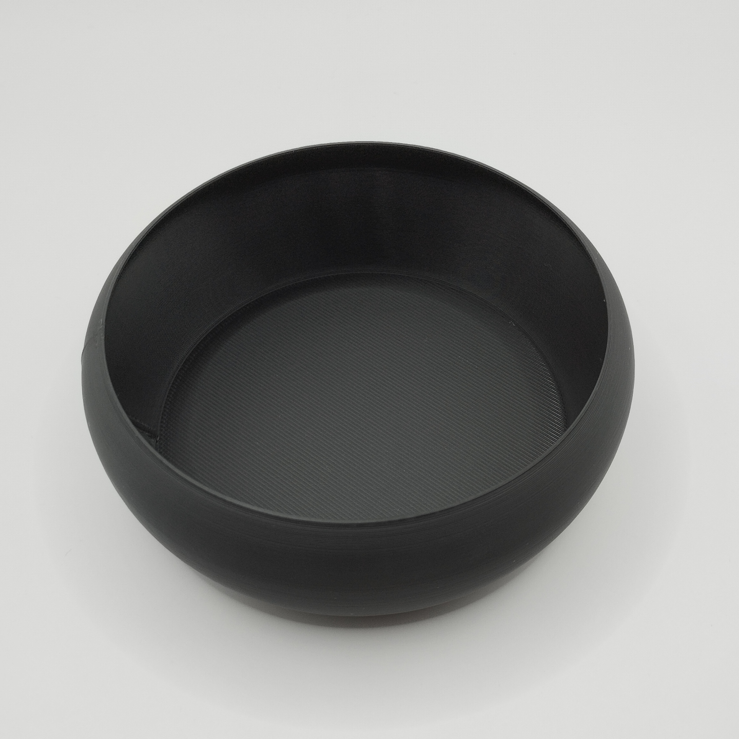 Minimalist key bowl on wooden shelf with keys and coins inside, beside a plant