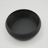Minimalist key bowl on wooden shelf with keys and coins inside, beside a plant