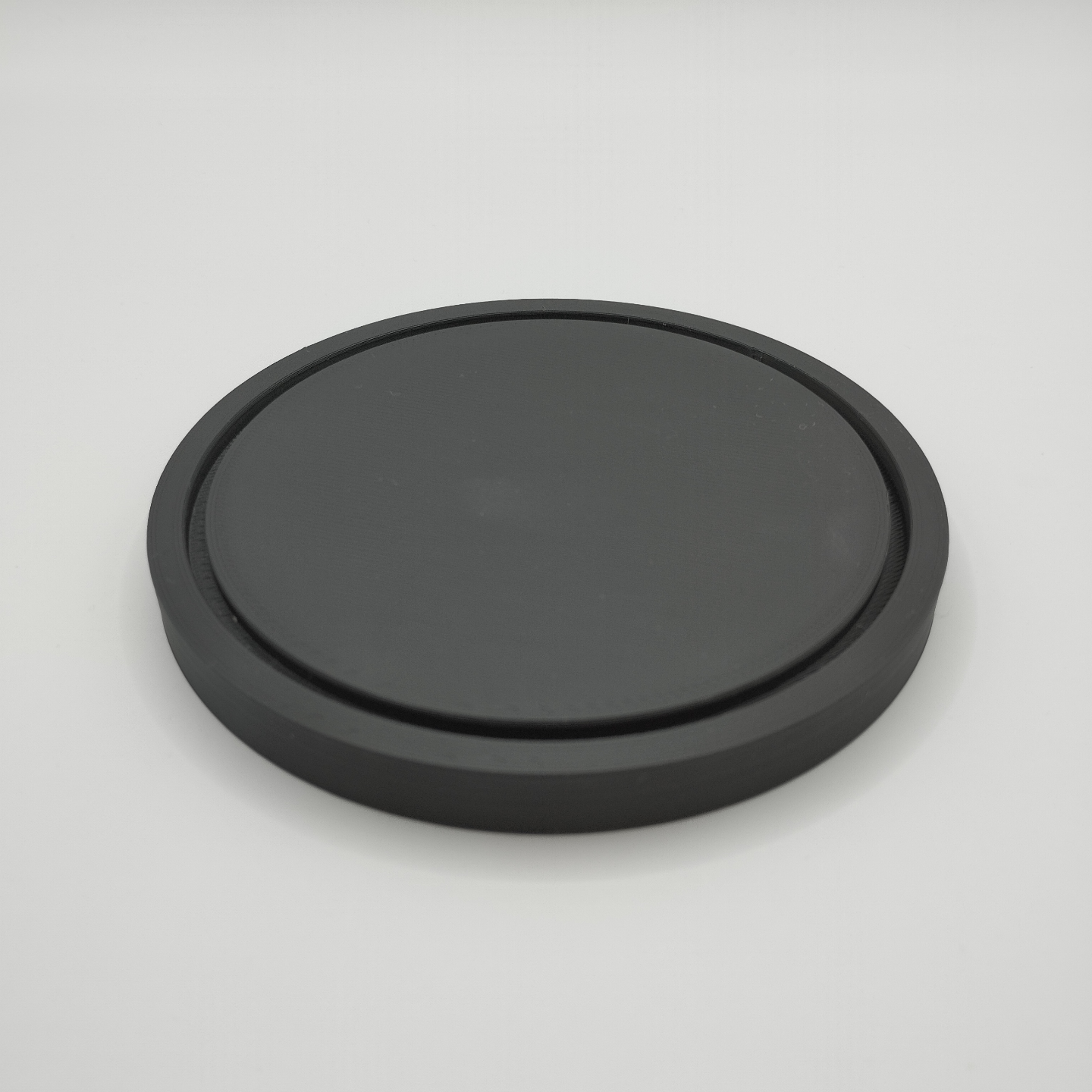 Minimalist round coaster beneath a warm ceramic mug on a wooden table