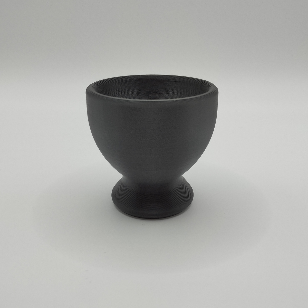 Two minimalist egg cups styled on a simple wooden table with fresh eggs