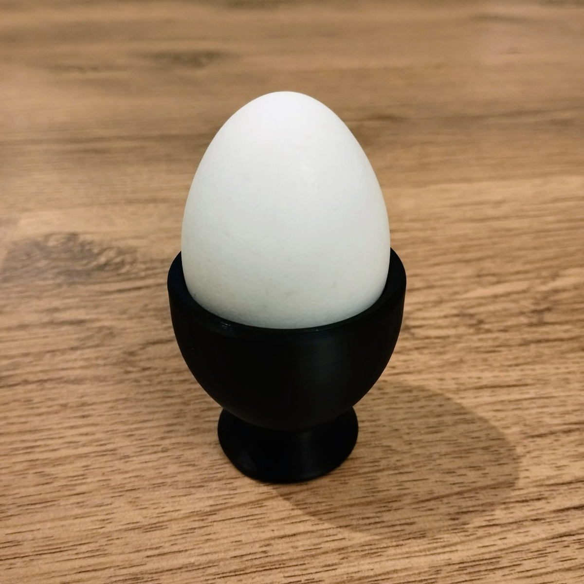 Close-up of a matte white minimalist egg cup showing clean cone form