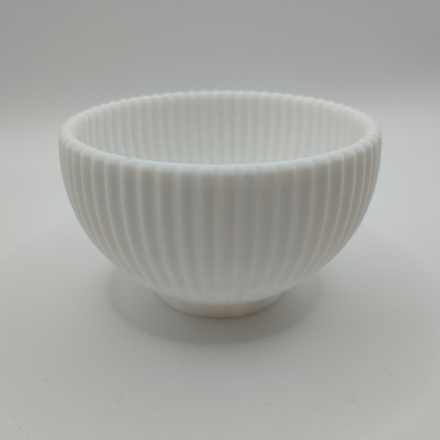 Round ribbed bowl displayed on wooden shelf with home decor