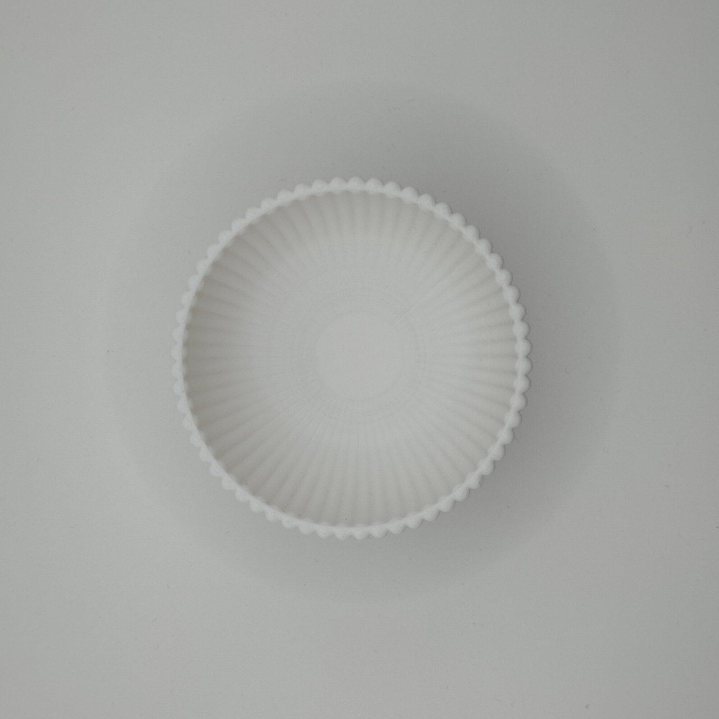 Soft light across ribbed bowl surface creating shadow texture