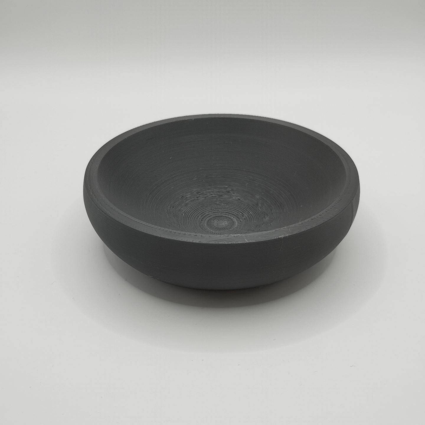 Detail of the flat bowl's smooth interior surface and clean edge profile