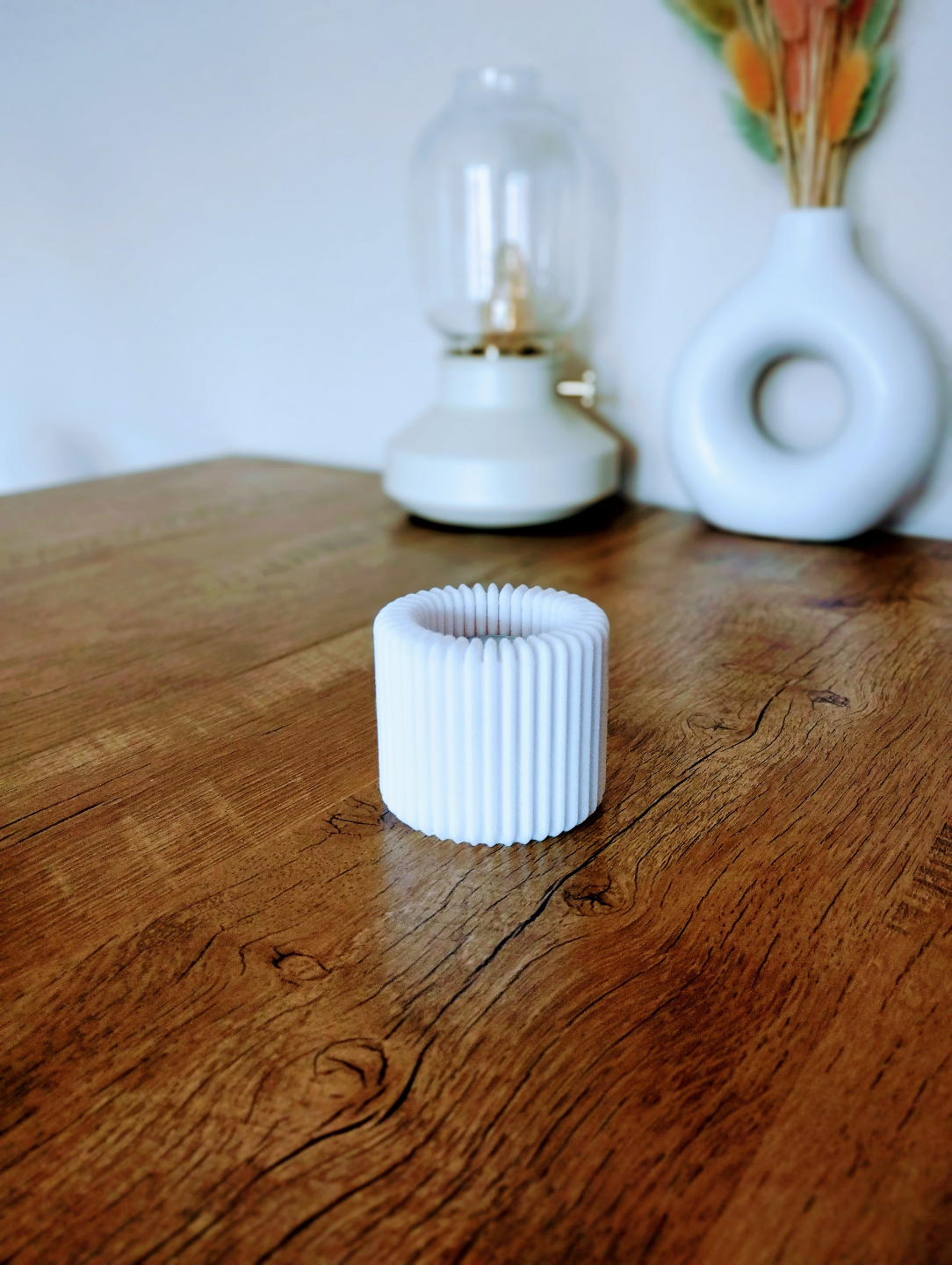 Ribbed tealight holder lit with warm LED candle on white shelf