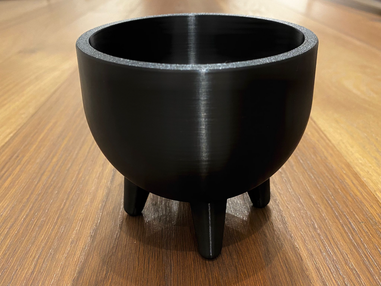 Mid-century plant pot with four feet shown in warm light, clean geometric lines