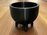Mid-century plant pot with four feet shown in warm light, clean geometric lines