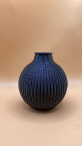 Ribbed modern vase displayed on wooden shelf with minimal styling