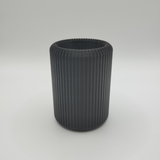 Ribbed toothbrush holder on bathroom counter with toothbrushes and toothpaste