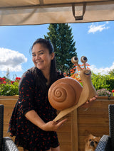 Person holding the giant garden snail statue in a garden, showing its 45 cm size