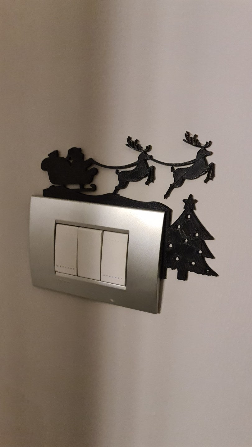 Weihnachtsmann im Schlitten mit Rentieren als Silhouette über einer Steckdose