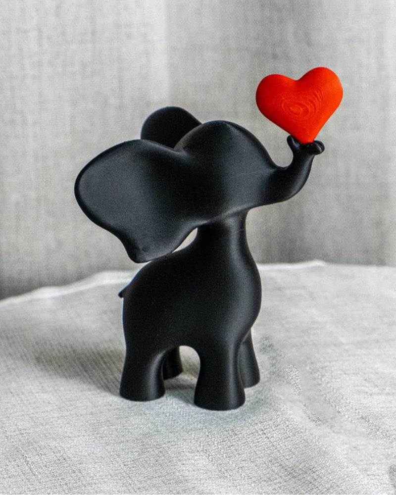 Close-up of elephant heart sculpture in black with red heart, on white surface