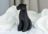 Detail of the fluid silhouette and matte black surface of a panther sculpture