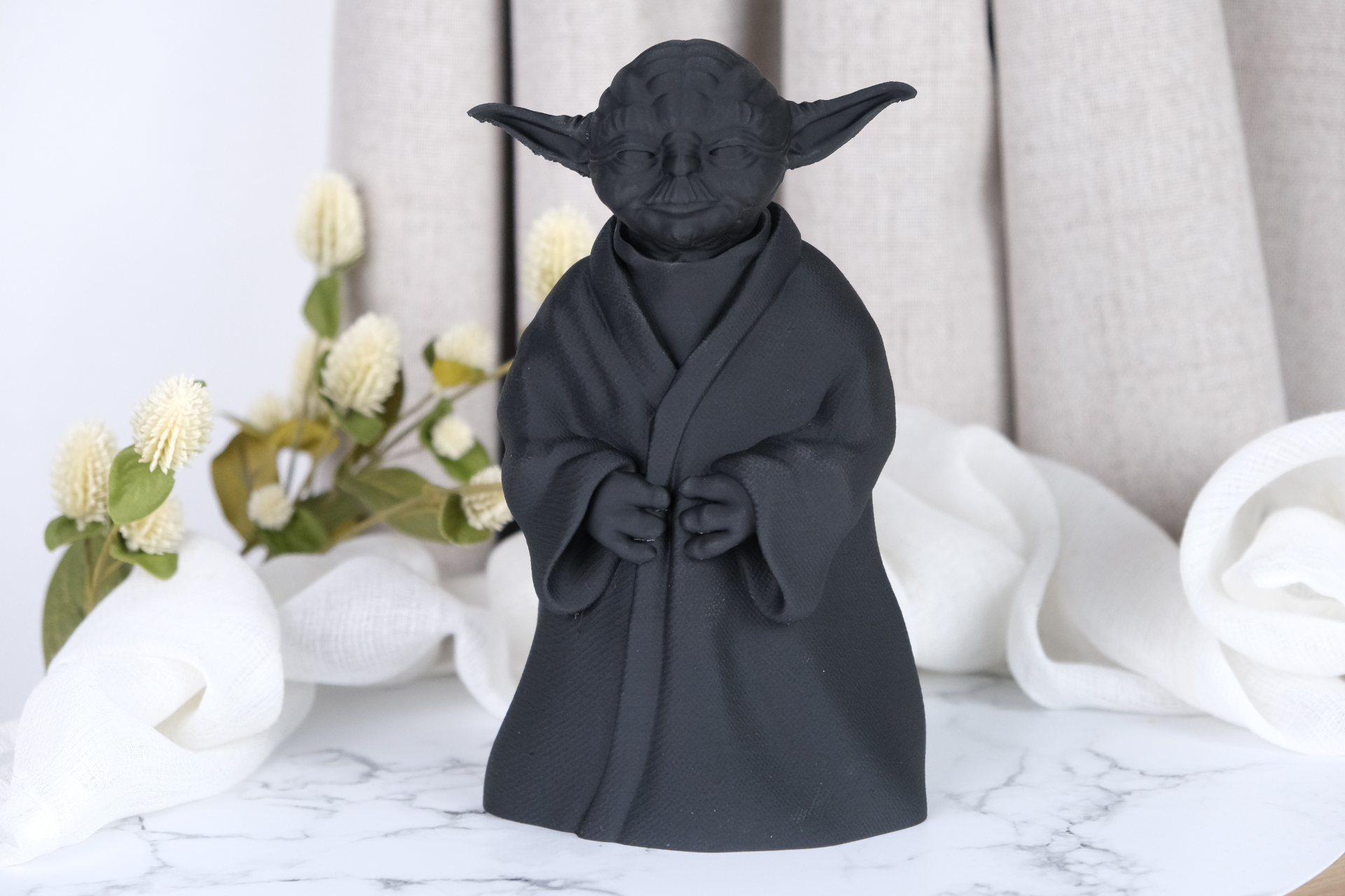 Yoda sculpture styled on a wooden desk beside a small plant and stacked books