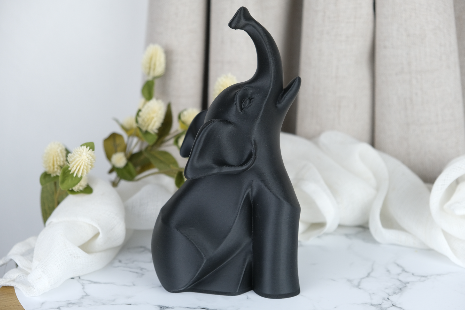 Black modern elephant sculpture styled on a minimalist desk next to a candle and small plant