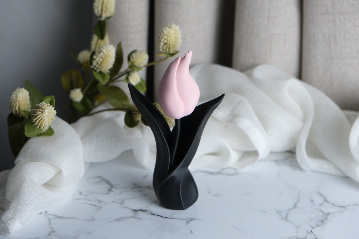 Tulip sculpture styled on a wooden shelf next to small ceramic objects and natural light