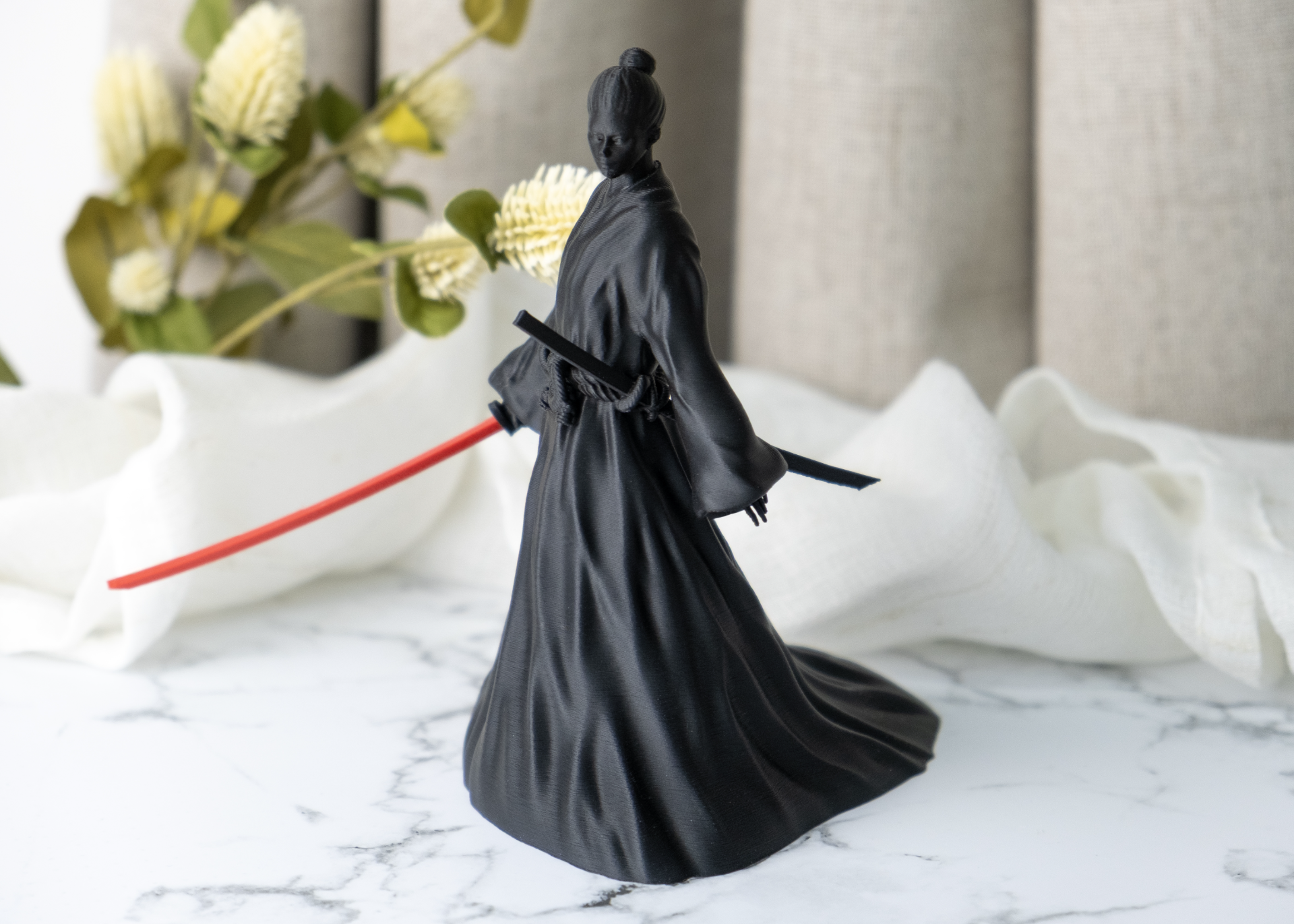 Onna-bugeisha figurine styled on a dark wood desk alongside minimal decor objects