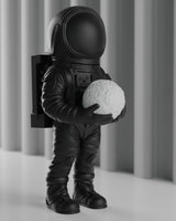 Matte black astronaut sculpture standing on a white desk — space decor figure, front view