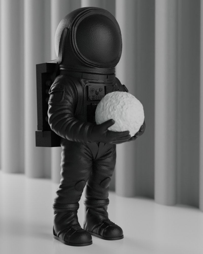Matte black astronaut sculpture standing on a white desk — space decor figure, front view