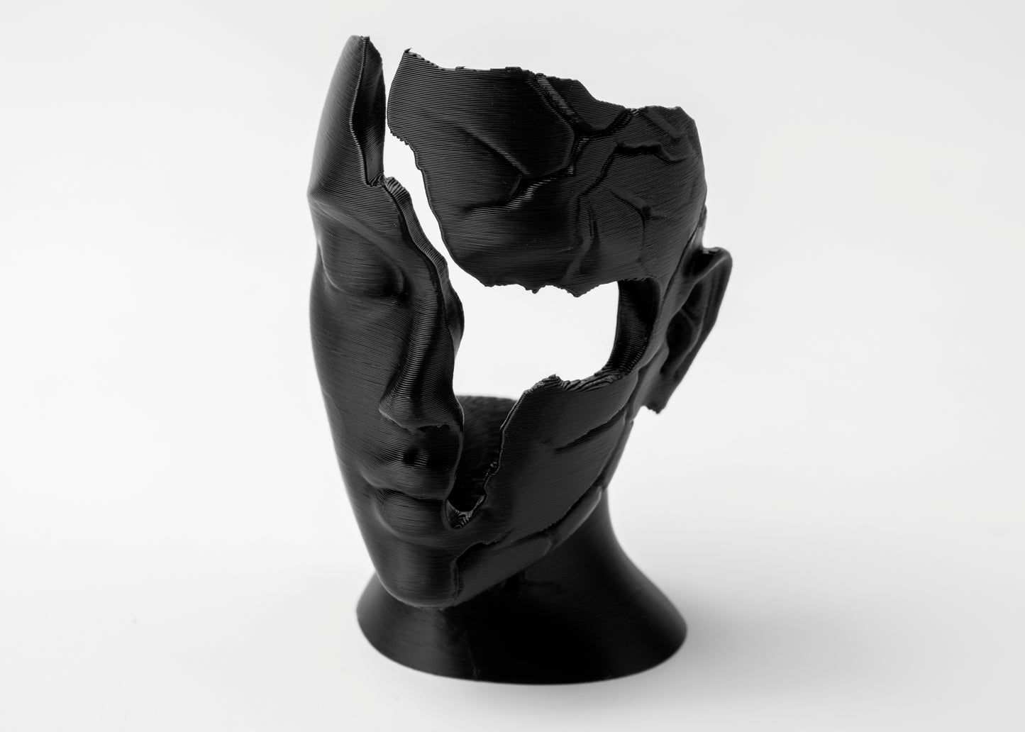 Abstract fractured female face sculpture styled on a wooden shelf beside matte ceramics