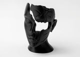 Abstract fractured female face sculpture styled on a wooden shelf beside matte ceramics