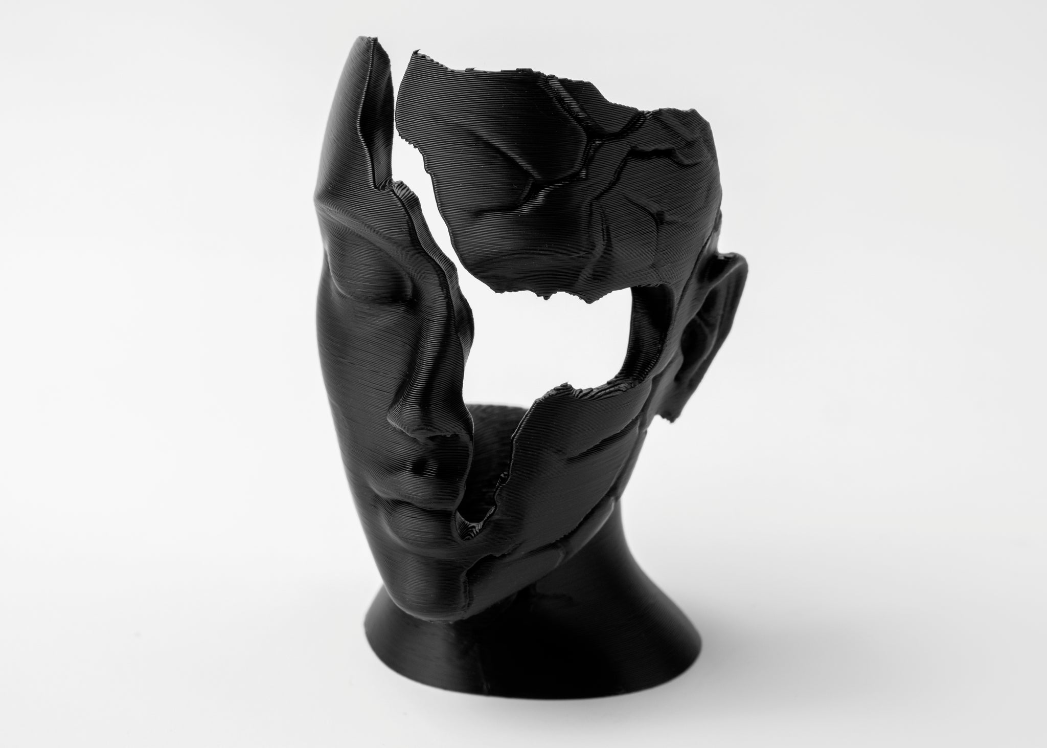Abstract fractured female face sculpture styled on a wooden shelf beside matte ceramics